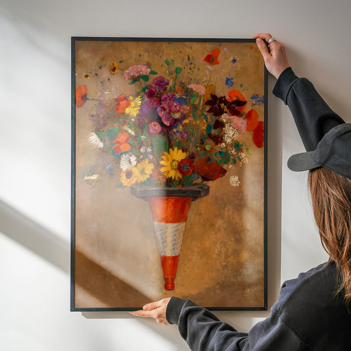 The print hung in a kitchen, a bright poppy and daisy bouquet in an orange traffic cone