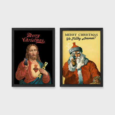 Set of 2 framed prints, festive prints: a "Merry Christmas" print with a classical Sacred Heart image; and a "Merry Christmas Ya Filthy Animal!" illustrated Santa print — unframed