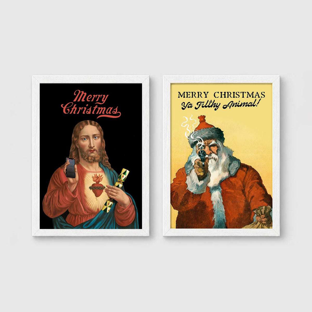 Set of 2 framed prints, festive prints: a "Merry Christmas" print with a classical Sacred Heart image; and a "Merry Christmas Ya Filthy Animal!" illustrated Santa print — unframed