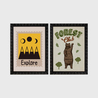 Set of 2 framed prints, stamp-style and illustrated kids prints: an "Explore" stamp-style icon illustration of mountains and moon phases; and a "Forest Club" illustration of a bear among trees — unframed
