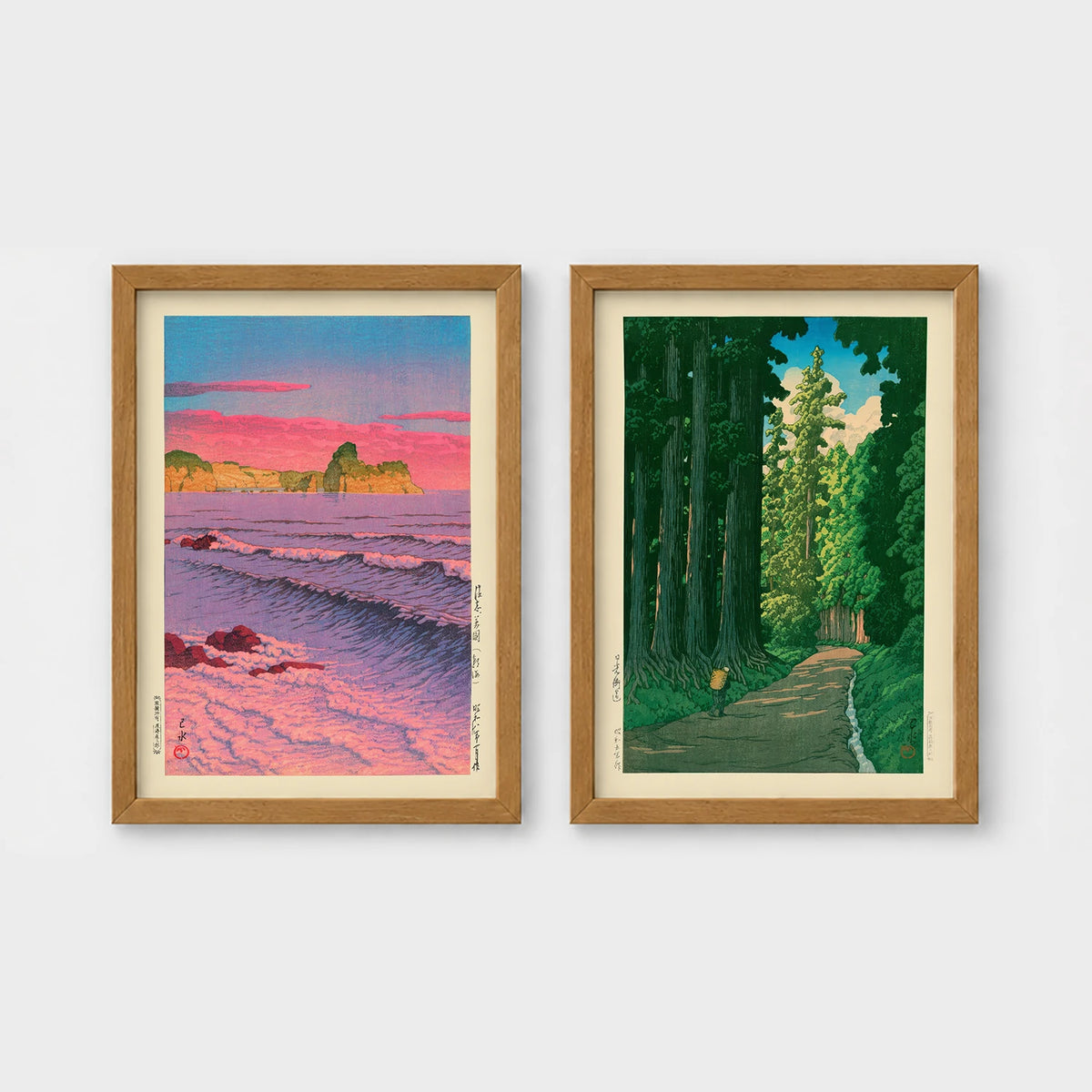 Set of 2 framed prints, Kawase Hasui Japanese woodblock prints: a pink sunset over ocean waves and cliffs; and a cedar forest path with a lone walker — unframed
