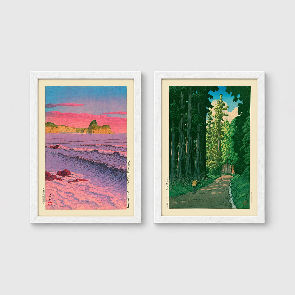 Set of 2 framed prints, Kawase Hasui Japanese woodblock prints: a pink sunset over ocean waves and cliffs; and a cedar forest path with a lone walker — unframed