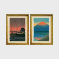 Set of 2 framed prints, Kawase Hasui Japanese woodblock prints: sailboats moored at a harbour at dusk; and Mount Fuji glowing red at sunset, reflected in the water — unframed