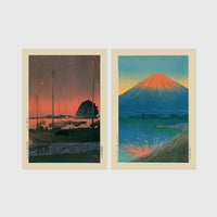 Set of 2 framed prints, Kawase Hasui Japanese woodblock prints: sailboats moored at a harbour at dusk; and Mount Fuji glowing red at sunset, reflected in the water — unframed