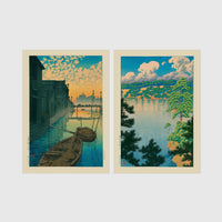 Set of 2 framed prints, Kawase Hasui Japanese woodblock prints: boats moored on a canal at dawn beneath a cloud-streaked sky; and a lake view framed by pine branches beneath drifting clouds — unframed