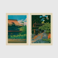 Set of 2 framed prints, Kawase Hasui Japanese woodblock prints: a temple building with a red roof against a blue sky; and a temple approach path with figures beneath trees — unframed