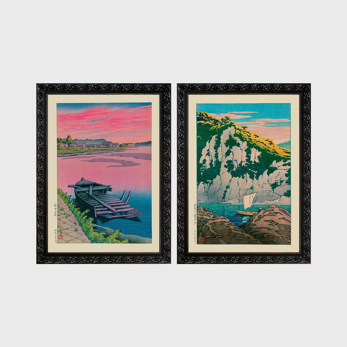 Set of 2 framed prints, Kawase Hasui Japanese woodblock prints: a pink sunset lake scene with a moored boat; and green coastal cliffs with a small sailboat — unframed