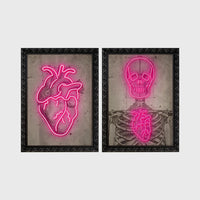 Set of 2 framed prints, neon anatomical illustrations: a neon pink anatomical heart illustration; and a neon pink skeleton skull and ribcage illustration — unframed