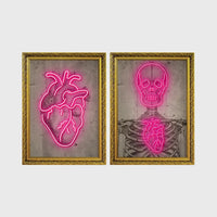 Set of 2 framed prints, neon anatomical illustrations: a neon pink anatomical heart illustration; and a neon pink skeleton skull and ribcage illustration — unframed
