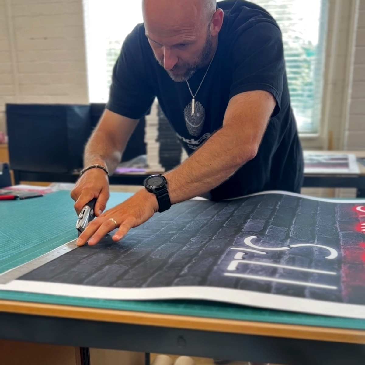 A person cutting out a large 100x150cm print by hand