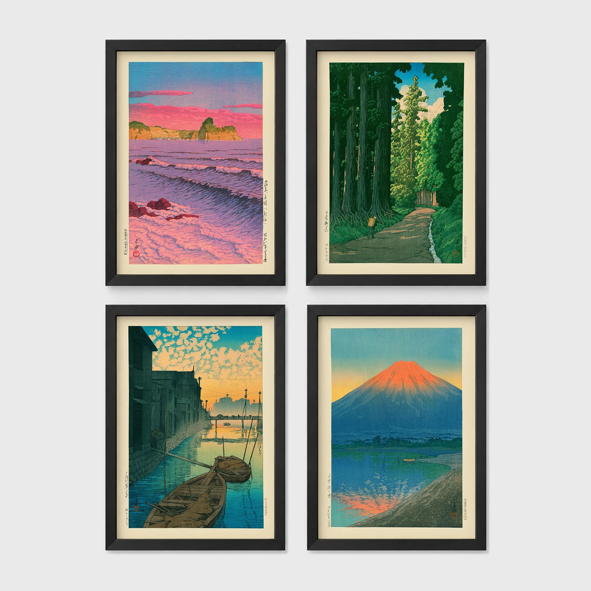Set of 4 framed prints, Kawase Hasui Japanese woodblock prints: pink sunset over ocean waves and cliffs; a cedar forest path with a lone walker; boats moored on a canal at dawn beneath a cloud-streaked sky; and Mount Fuji glowing red at sunset, reflected in the water — unframed