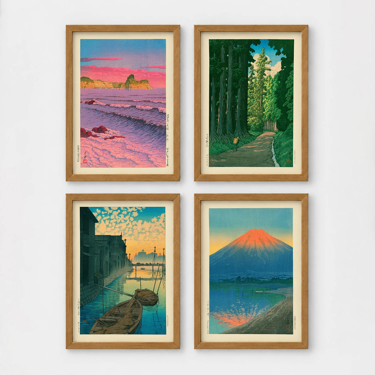Set of 4 framed prints, Kawase Hasui Japanese woodblock prints: pink sunset over ocean waves and cliffs; a cedar forest path with a lone walker; boats moored on a canal at dawn beneath a cloud-streaked sky; and Mount Fuji glowing red at sunset, reflected in the water — unframed