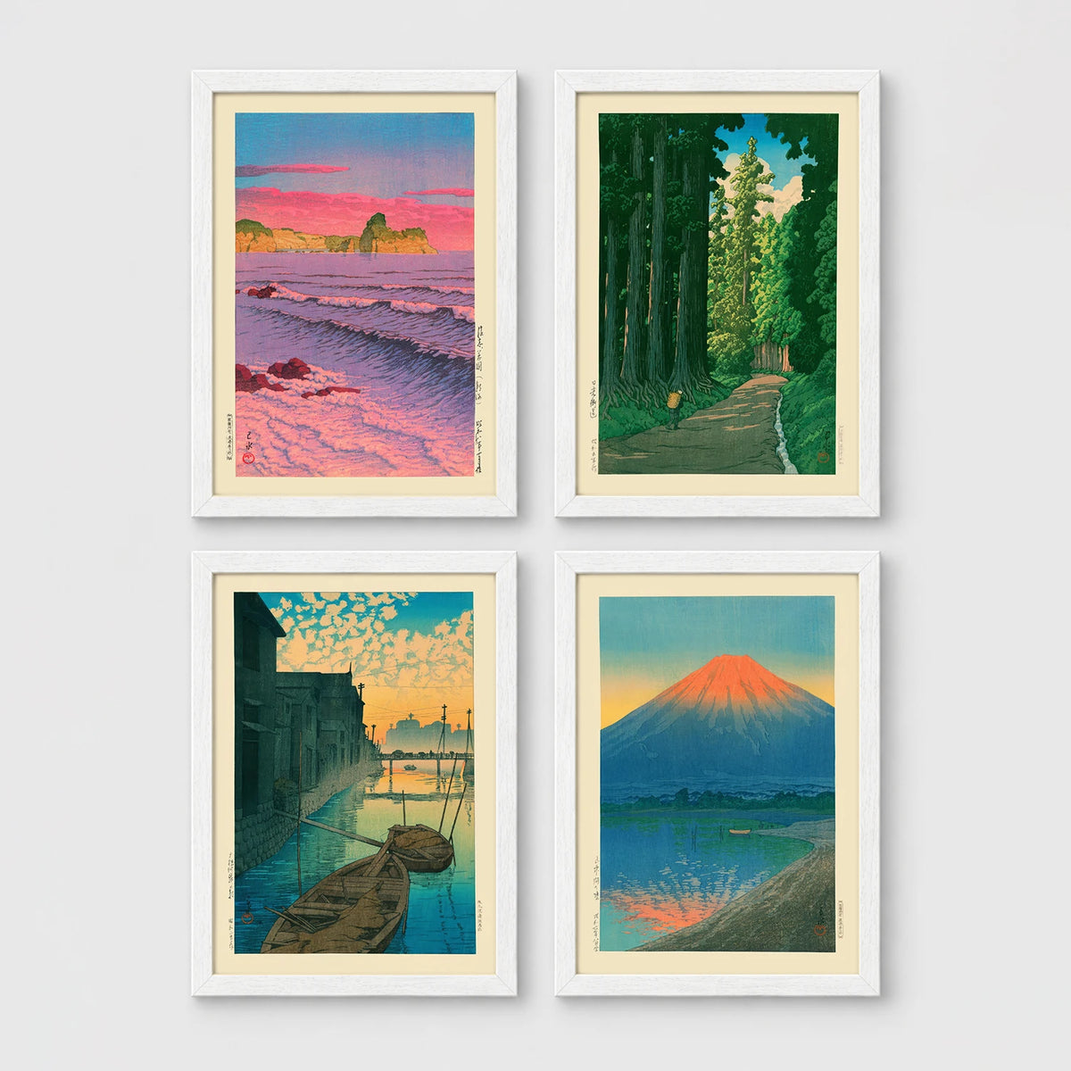 Set of 4 framed prints, Kawase Hasui Japanese woodblock prints: pink sunset over ocean waves and cliffs; a cedar forest path with a lone walker; boats moored on a canal at dawn beneath a cloud-streaked sky; and Mount Fuji glowing red at sunset, reflected in the water — unframed