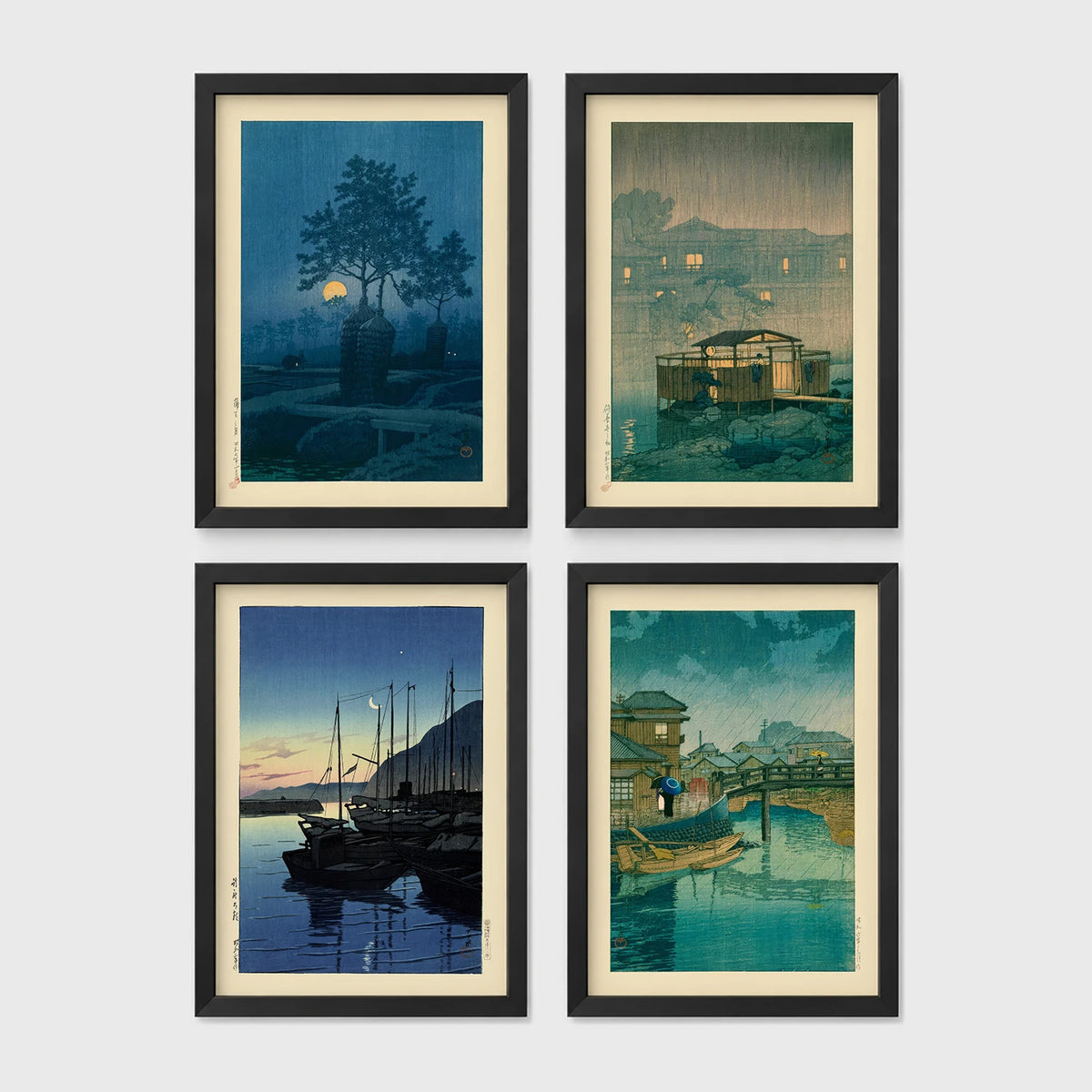 Set of 4 framed prints, Kawase Hasui Japanese woodblock prints (night scenes): a moonlit tree and stone lantern at night; a misty rain-soaked house with lantern light at dusk; sailboats moored at a harbour at dawn; and a canal bridge scene with a figure and umbrella at twilight — unframed