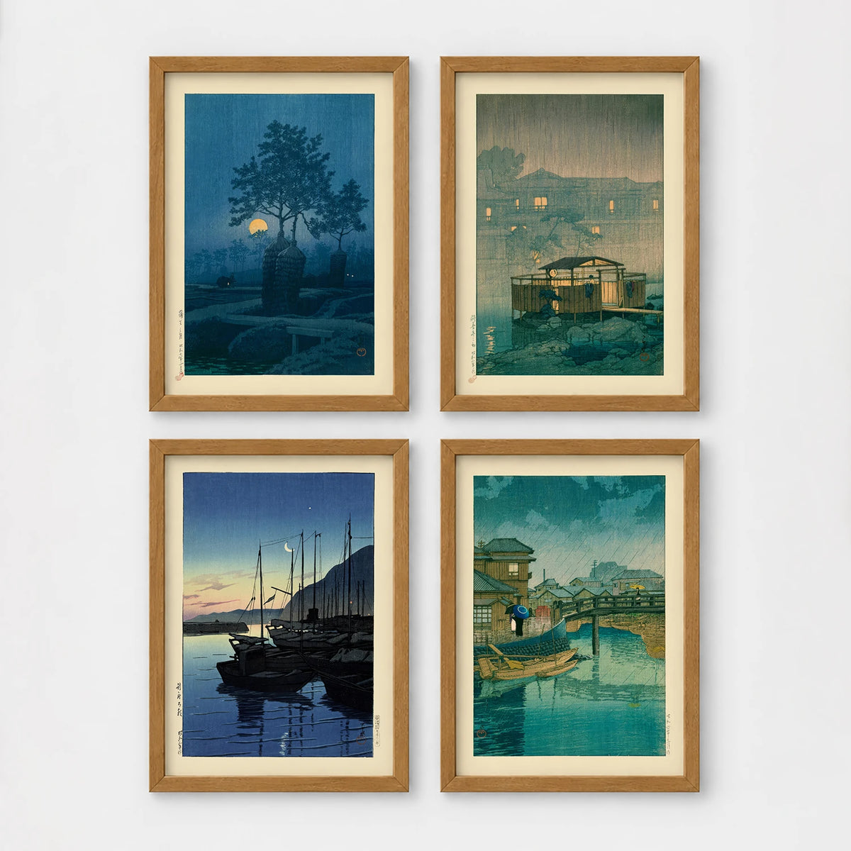 Set of 4 framed prints, Kawase Hasui Japanese woodblock prints (night scenes): a moonlit tree and stone lantern at night; a misty rain-soaked house with lantern light at dusk; sailboats moored at a harbour at dawn; and a canal bridge scene with a figure and umbrella at twilight — unframed