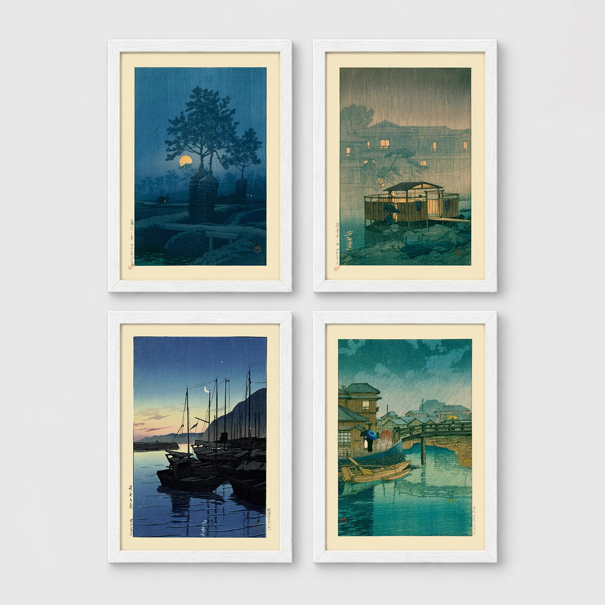 Set of 4 framed prints, Kawase Hasui Japanese woodblock prints (night scenes): a moonlit tree and stone lantern at night; a misty rain-soaked house with lantern light at dusk; sailboats moored at a harbour at dawn; and a canal bridge scene with a figure and umbrella at twilight — unframed