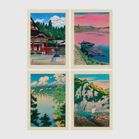 Set of 4 framed prints, Kawase Hasui Japanese woodblock prints: a red shrine framed by pine trees under a blue sky; a pink sunset over a lake with a moored boat; a lake view framed by pine branches beneath drifting clouds; and green coastal cliffs with a waterfall over turquoise water — unframed