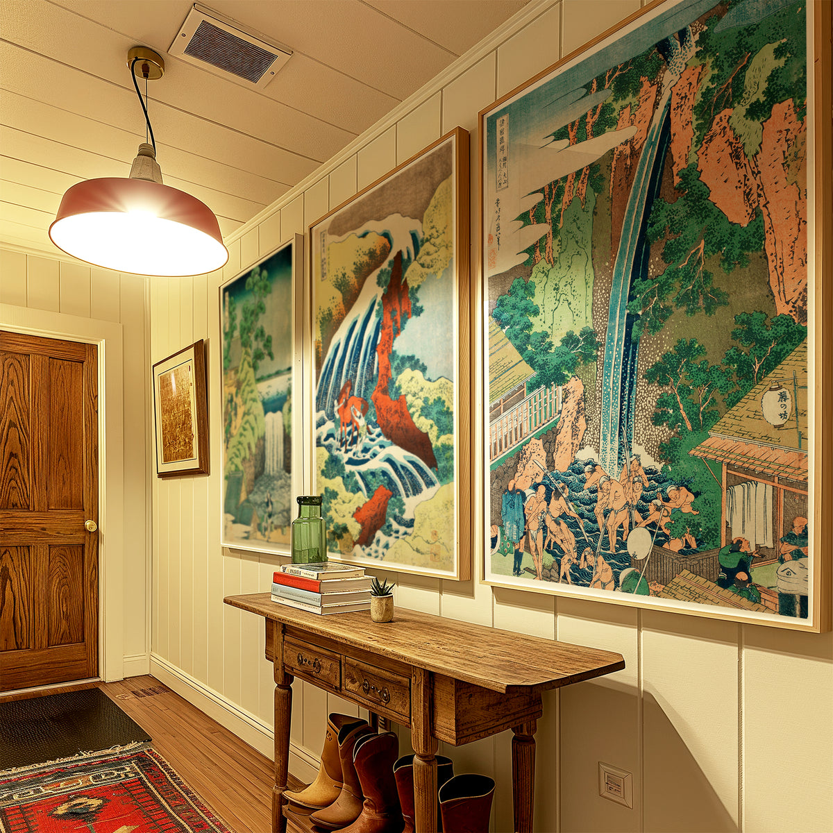 A hallway with three large framed Japanese-style art prints on the wall above a wooden console table. The prints depict a waterfall, a red-and-blue bird, and a mountain landscape.