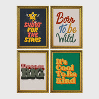 Set of 4 framed prints, retro groovy typographic quote prints: "Shoot For The Stars" typography with a star character; "Born To Be Wild" typography; "Dream Big" typography; and "It's Cool To Be Kind" typography — unframed