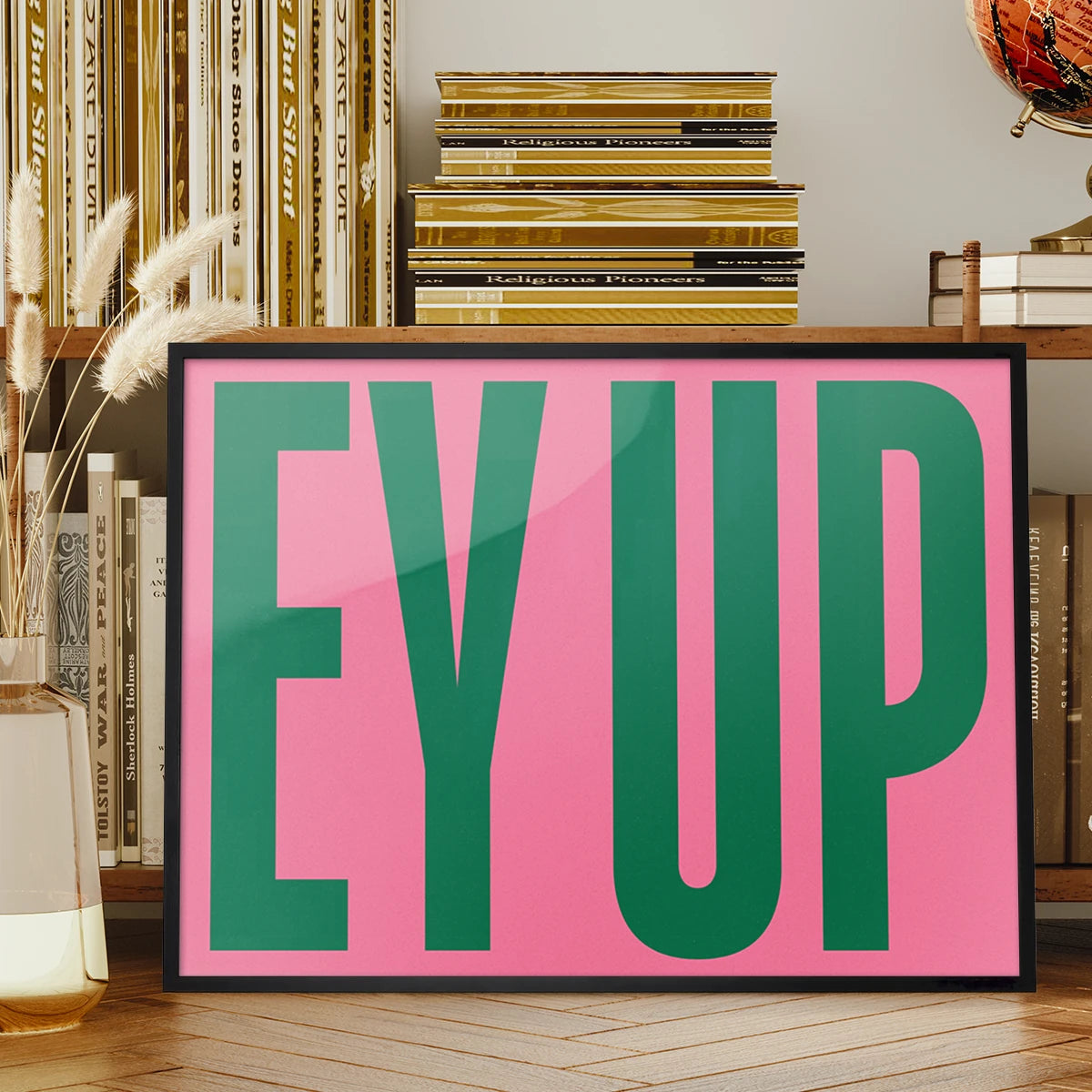 Ey Up typography print displayed on a living room wall, landscape green and pink lettering