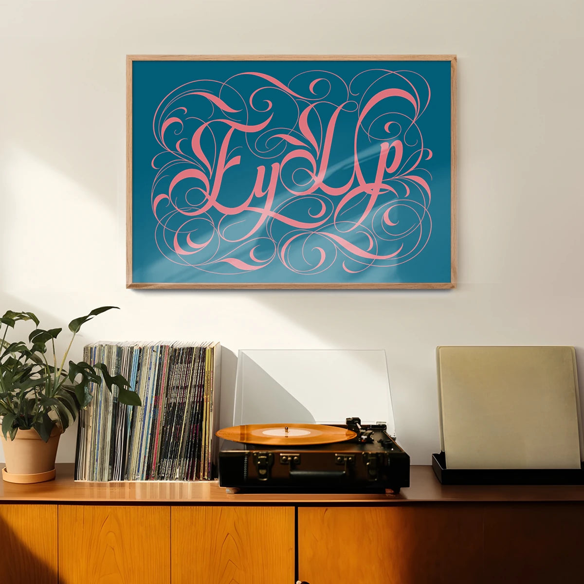 Ornate calligraphy lettering print on teal hung in a welcoming hallway