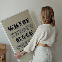 Where There's Muck There's Brass print displayed on a living room wall as bold typography wall art