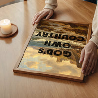 The print showing a coastal abbey scene with bold lettering in a bedroom